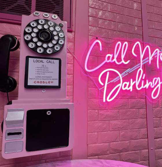 pink wall telephone beside a pink neon sign