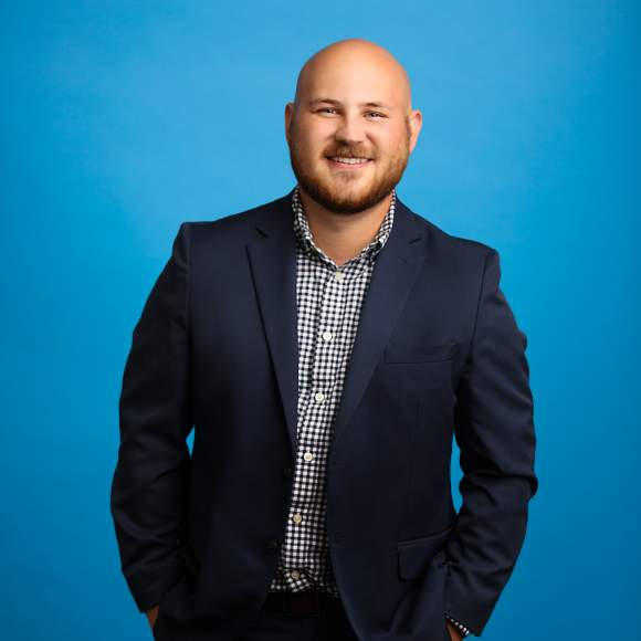 Zach Wellman headshot on blue background