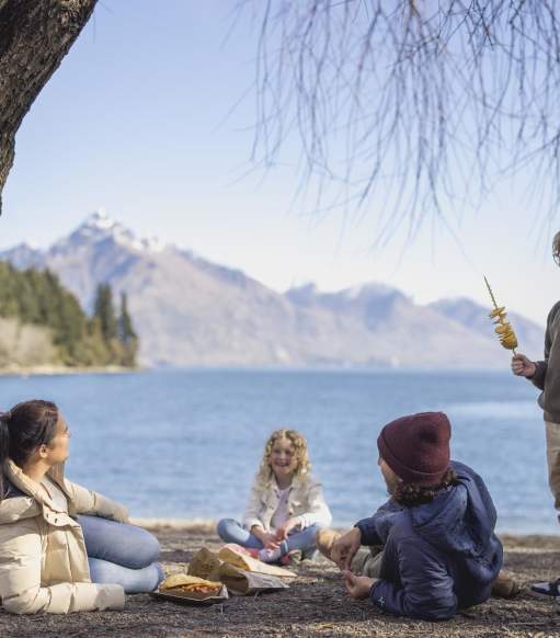 Family eating fish and chips at Queenstown Bay beach