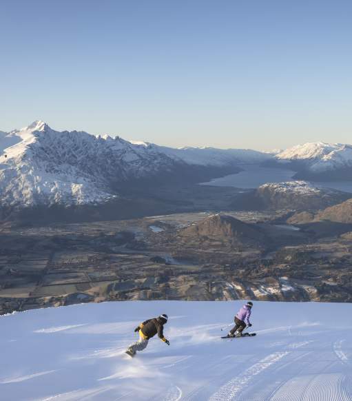 Snowboarding at Coronet Peak with lake and mountains in background