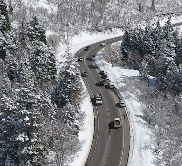 Cars driving on a slightly wet road in a snowy canyon