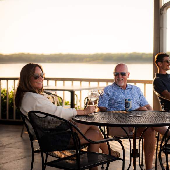 Three people enjoying drinks on the patio at the Point Restaurant which overlooks Lake Texoma
