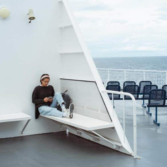 A women sitting outside on the ferry.