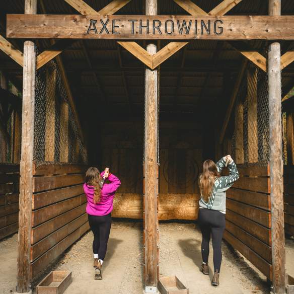 Two people getting ready to throw axes.