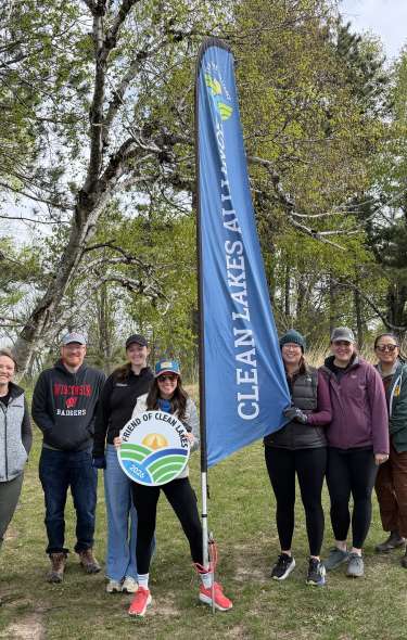 Voluntourism and volunteers in Madison at Holy Wisdom Monastery holding a Clean Lakes Alliance sign