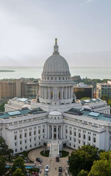 An aerial view of the Wisconsin State Capitol building with a lake in the background