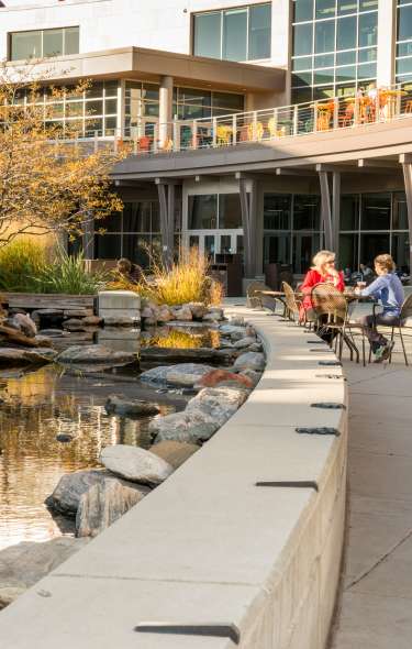 Two adults sit at a table next to a water fixture on the University of Wisconsin campus