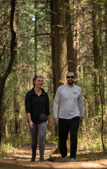 A couple walks along a trail in the woods