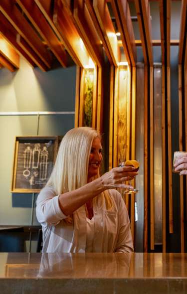 Two white women cheers cocktails at the bar at Yahara Bay Distillery