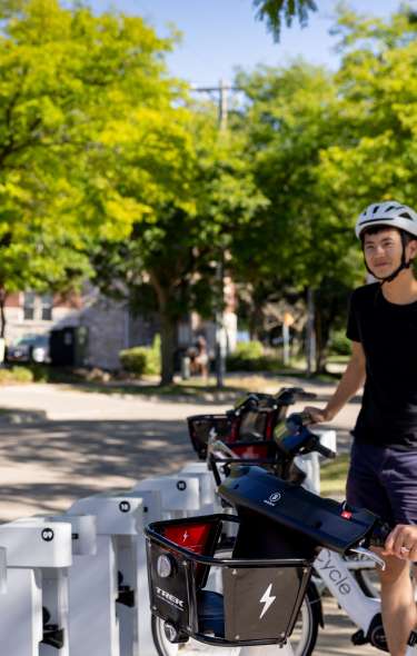 Two cyclists at an e-bike rental station exploring Madison transportation options