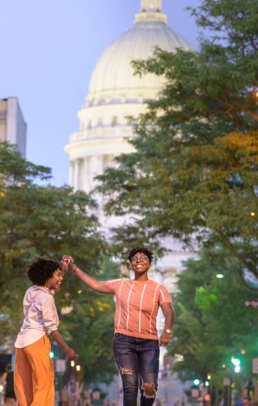 Two couples walk down State Street with the Capitol in the background at night