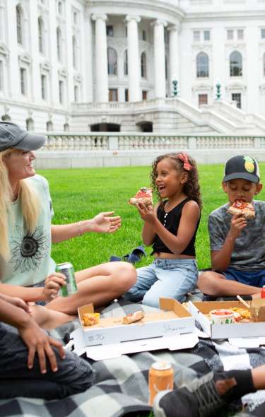 A family enjoys a picnic on the lawn of the Wisconsin State Capitol, one of Madison's most popular attractions