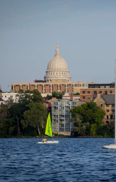 Sailboats sail on the lake with the Capitol on the horizon