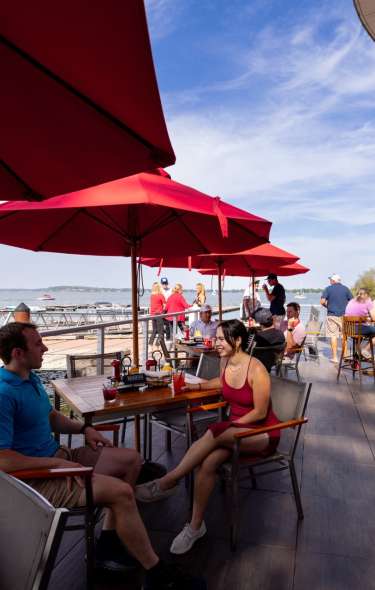 A couple sits at a table on the patio of The Boathouse at The Edgewater. The patio is alongside Lake Mendota