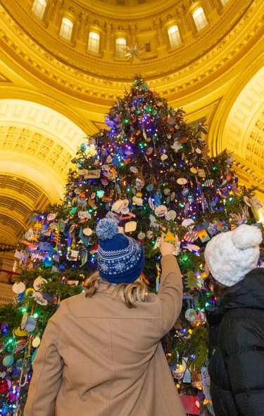 Two women look up at the large holiday tree in the Wisconsin State Capitol routunda