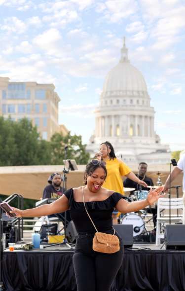 Conference attendees dancing on Monona Terrace rooftop with Capitol Building in the background