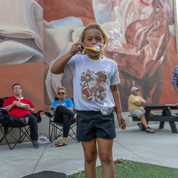 Kid blowing bubbles in front of mural