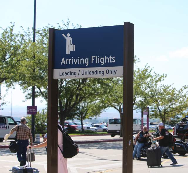 The external arrival zone at Rapid City Regional Airport as passengers with luggage wait for transportation.