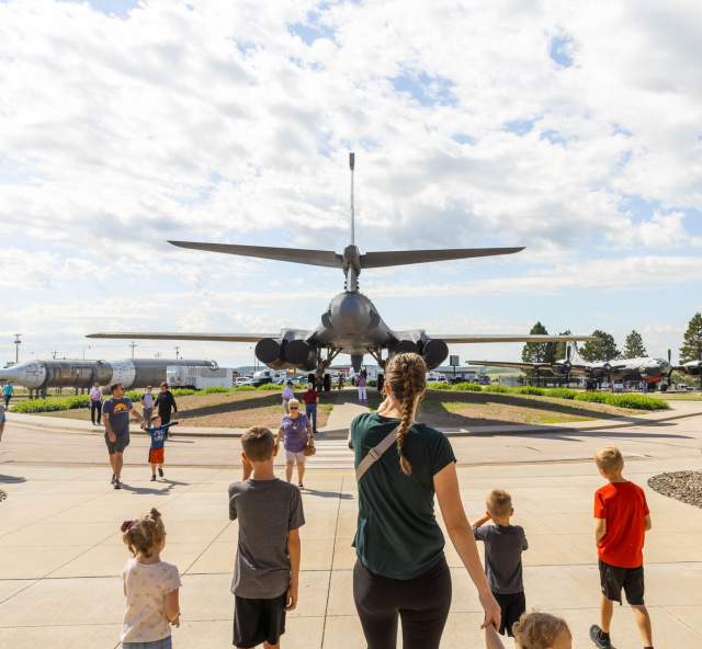 family walking behind the b1 plane on display at the south dakota air and space museum