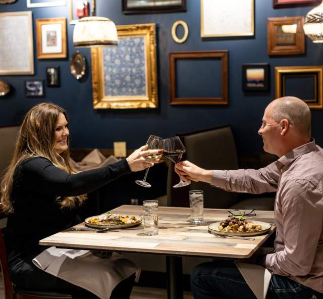 couple cheers-ing wine over a meal at tandoor bocado in downtown rapid city, sd