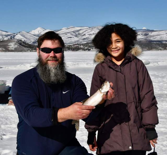 Family holding up a fish after ice fishing