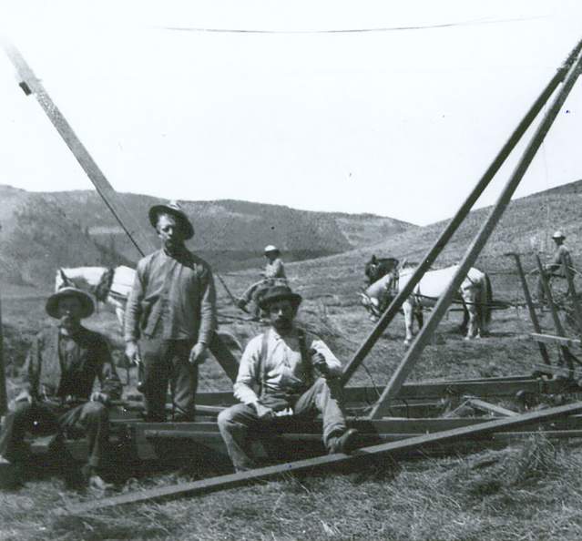 Historic photo of men bailing hay