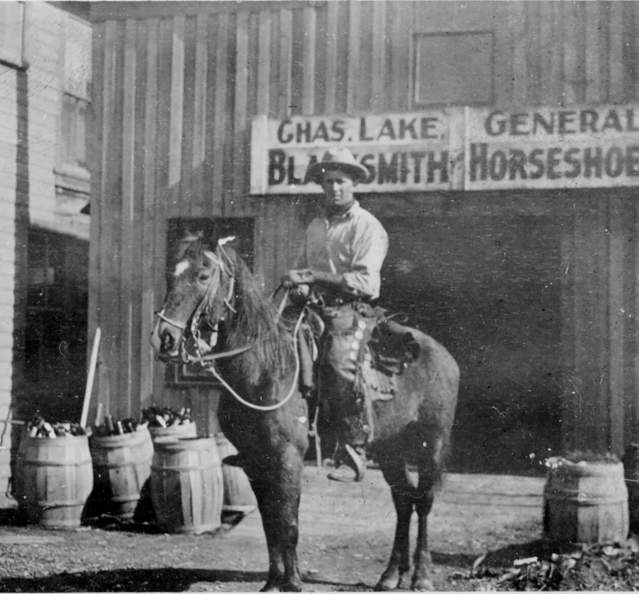 Historic photo of man in front of blacksmith shop c. 1914