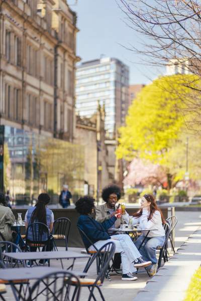Group of friends sat outside restaurant in the sun in Manchester