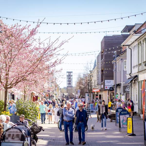 Mennesker som går i gågata og sitter på uteserveringen i Sarpsborg sentrum. Foto.