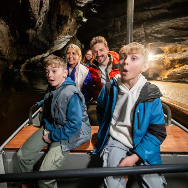 Visitors travelling by boat through the Marble Arch Caves, surrounded by towering limestone formations deep beneath the Fermanagh countryside.
