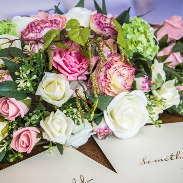 A bunch of pink and white flowers adorn a table for a wedding ceremony