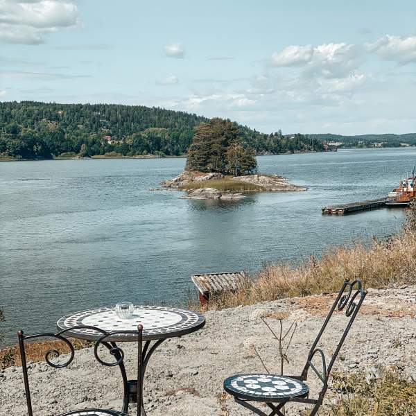 Kafésett på uteserveringen på Furuholmen, med utsikt over Glomma en solskinnsdag. Foto.
