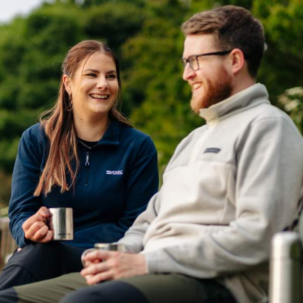 A couple enjoying a flask of hot drinks, sat on a bench taking a break from walking in the Yorkshire Wolds.