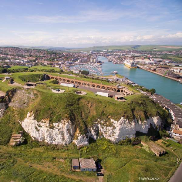 Aerial view of the grounds and red brick buildings of Newhaven Fort with sea in the distance