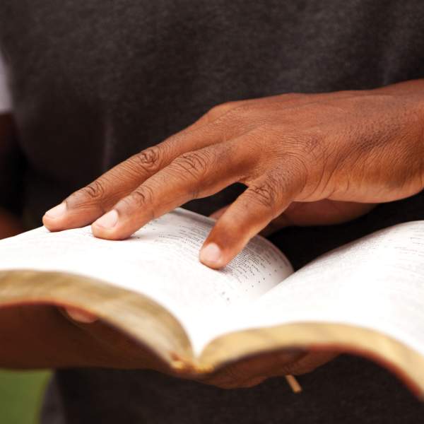 An african american man holding an open book.