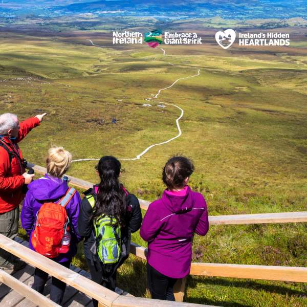 Group of walkers looking out over the landscape from the boardwalk at Cuilcagh Mountain.