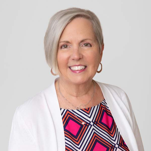 A woman with gray hair wearing a bright pink dress