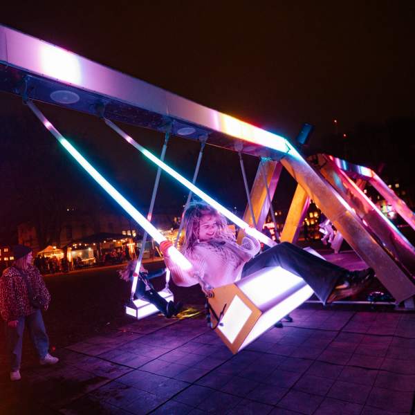 A young girl on a light up swing in the dark