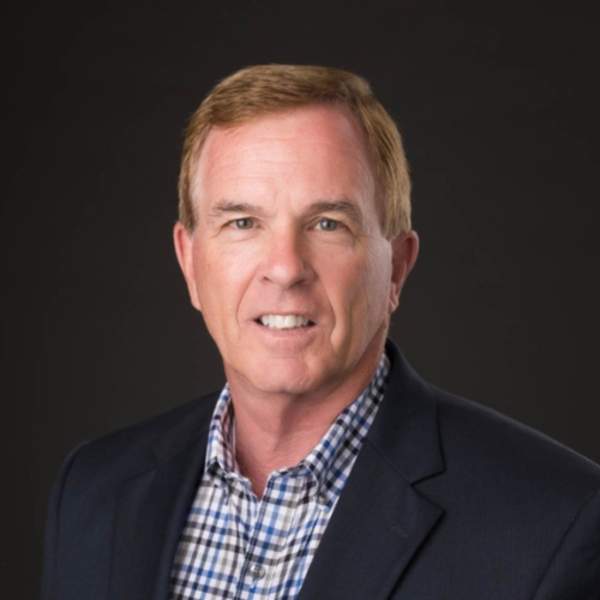 Professional headshot of man wearing black suit with checkered blue button down.