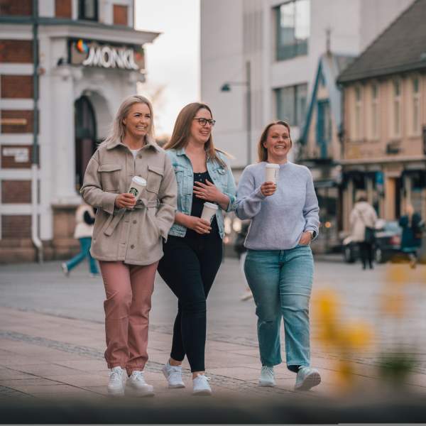 tre jenter som går med kaffe