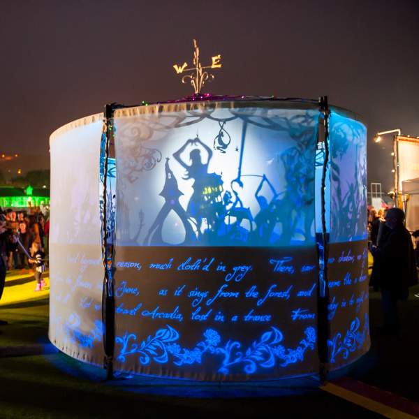 A light installation presenting a shadow puppet show with people watching
