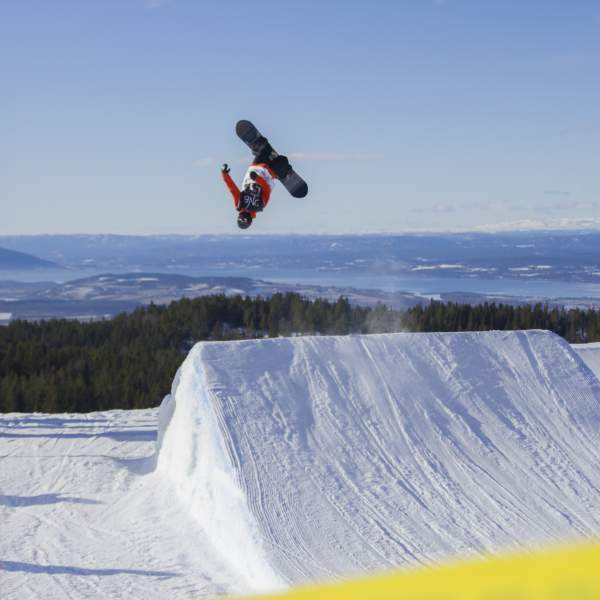 En snowboarder hopper høyt og tar en backflip i Ringkollen Alpintpark