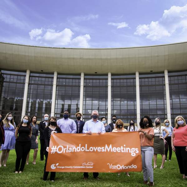 The Visit Orlando team holding a #OrlandoLovesMeetings banner in front of the Orange County Convention Center for Global Meetings Industry Day