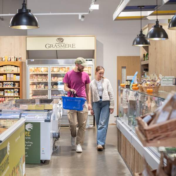 two people in farm shop with basket in hand surrounded by local produce