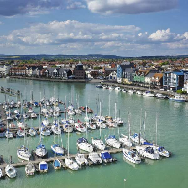 Yachts moored on the river at Littlehampton harbour, with riverside apartments on the opposite side