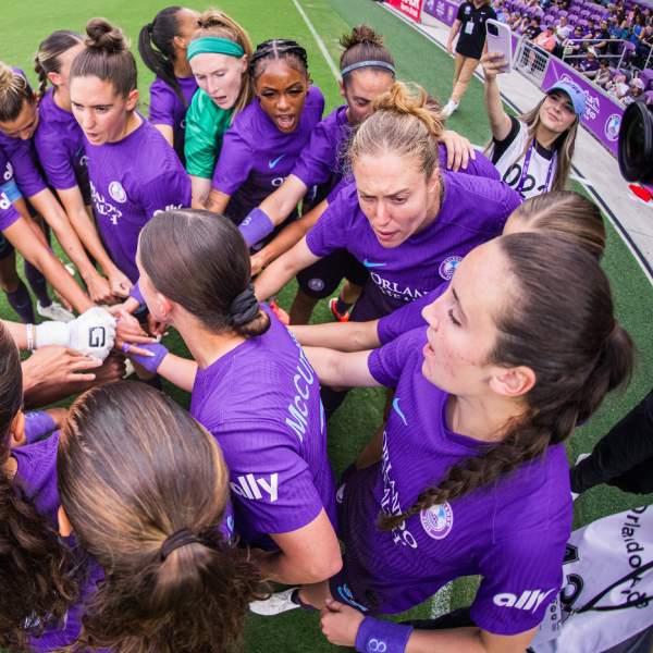 Members of the Orlando Pride National Women's Soccer League team huddle before a match.