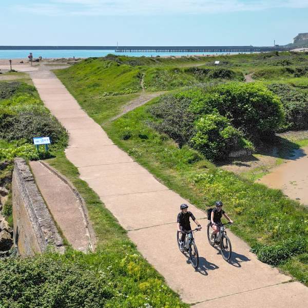 Aerial view of Tides Mill with cyclists on the path cycling away from the sea which can be seen in the distance