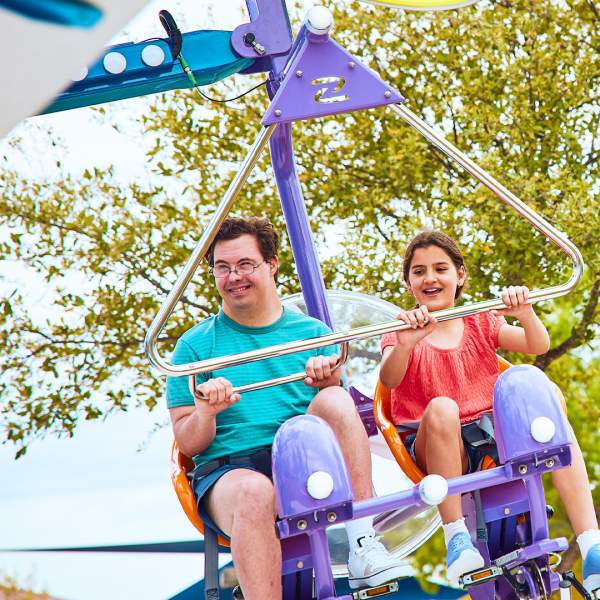 Boy and girl on air ride with trees behind them