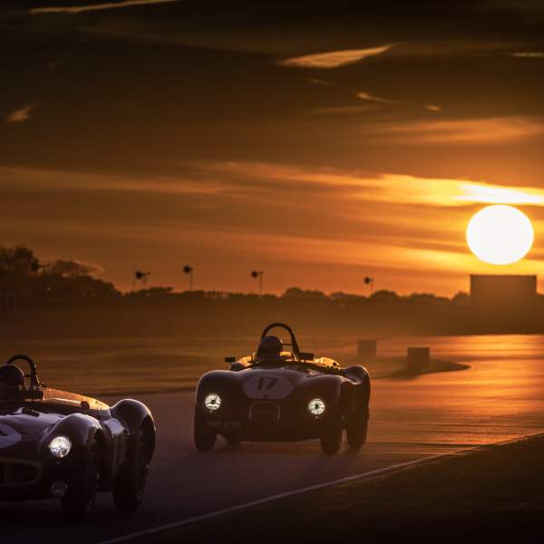 Cars race on the circuit at sunset at Goodwood Revival in Sussex