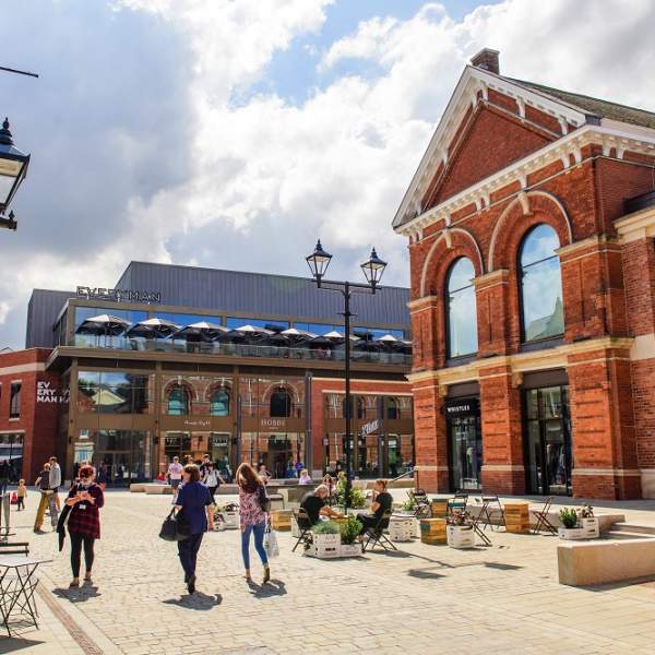 lively scene of Exchange Square in the Cornhill Quarter with people walking, shops in distance and clouds in the sky